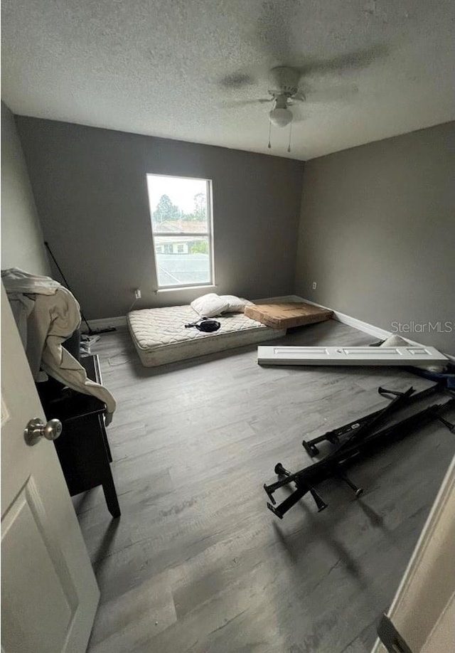 bedroom with ceiling fan, light hardwood / wood-style floors, and a textured ceiling