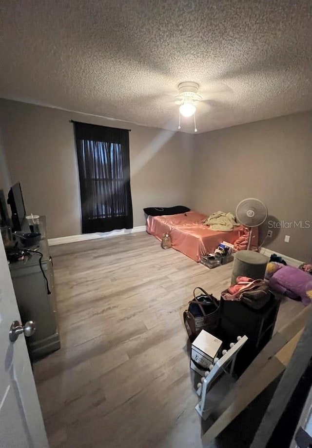 bedroom with wood-type flooring, ceiling fan, and a textured ceiling