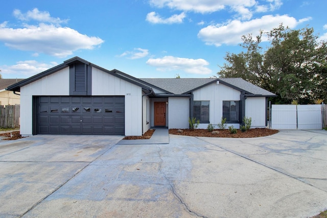 view of front of home featuring a shingled roof, concrete driveway, fence, and an attached garage