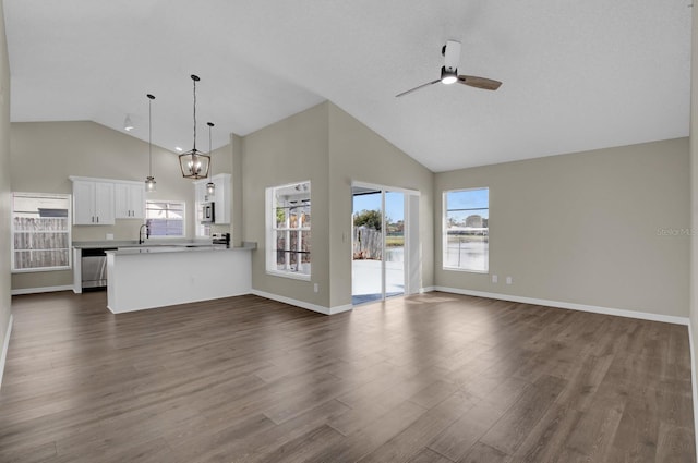 unfurnished living room with baseboards, a ceiling fan, dark wood-style flooring, high vaulted ceiling, and a sink