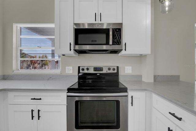 kitchen with appliances with stainless steel finishes, white cabinets, and light stone countertops