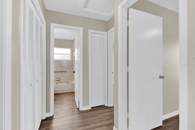 hallway with dark wood-style floors, attic access, a textured ceiling, and baseboards