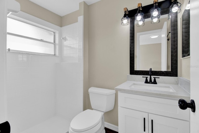 bathroom featuring toilet, a tile shower, and vanity