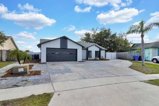 view of front of home with driveway, fence, an attached garage, and central air condition unit