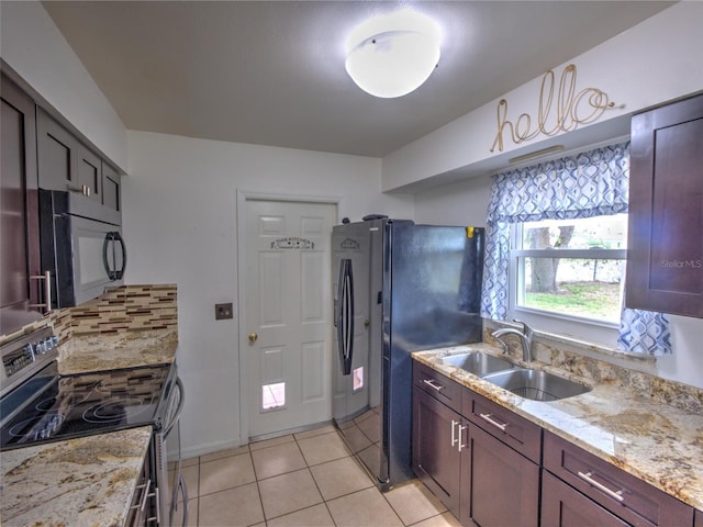 kitchen featuring light stone countertops, sink, light tile patterned floors, and black appliances