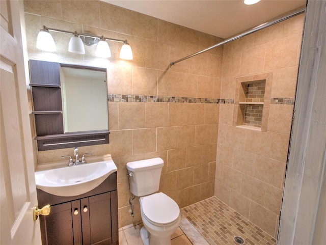 bathroom featuring vanity, tile patterned floors, toilet, and a tile shower