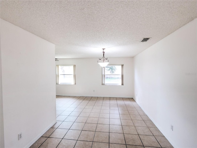 tiled spare room featuring plenty of natural light and a textured ceiling