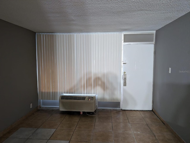 unfurnished room with tile patterned floors, a textured ceiling, and an AC wall unit