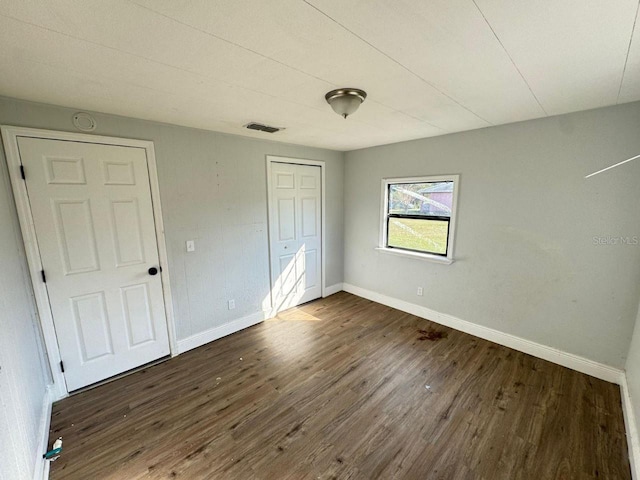 unfurnished bedroom with dark hardwood / wood-style floors and a closet