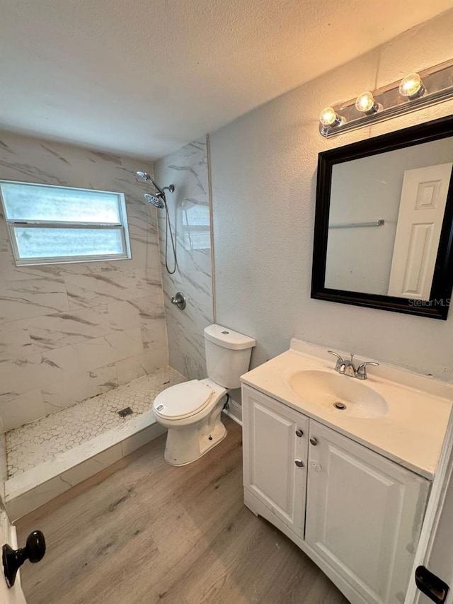 bathroom with vanity, hardwood / wood-style floors, a textured ceiling, and tiled shower