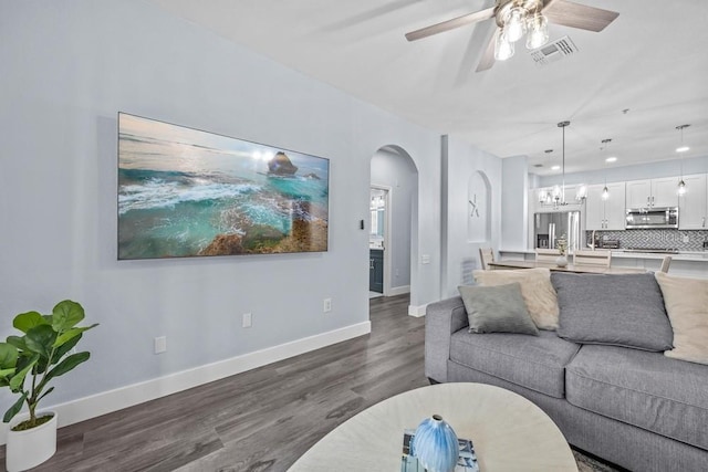 living room with ceiling fan with notable chandelier and dark wood-type flooring