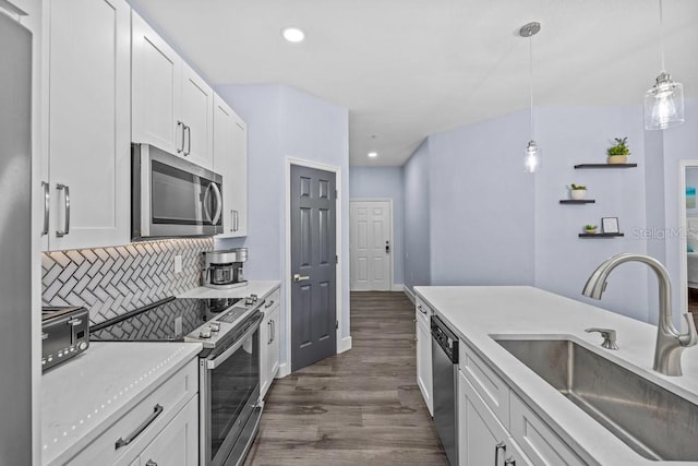 kitchen with pendant lighting, sink, appliances with stainless steel finishes, white cabinets, and decorative backsplash