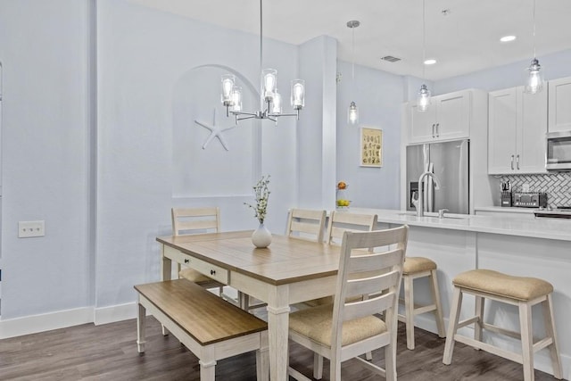 dining area featuring dark hardwood / wood-style floors, sink, and a chandelier