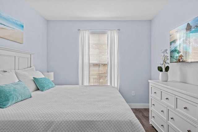 bedroom with multiple windows and dark hardwood / wood-style floors