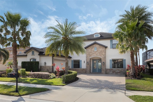 view of front of home featuring a garage, stone siding, driveway, and stucco siding