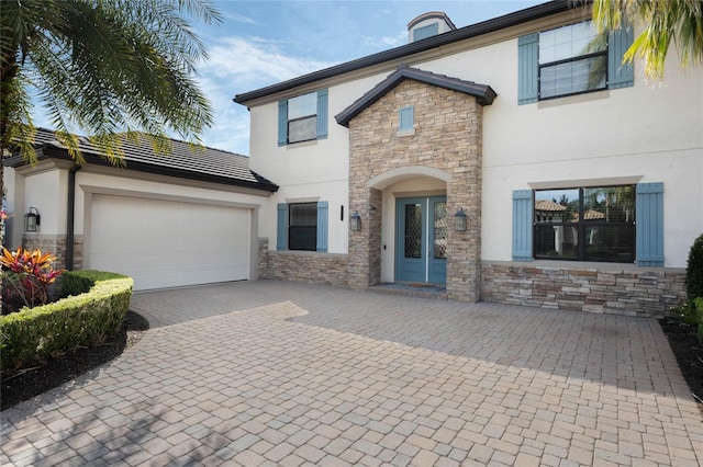 view of front of home featuring stone siding, decorative driveway, an attached garage, and stucco siding