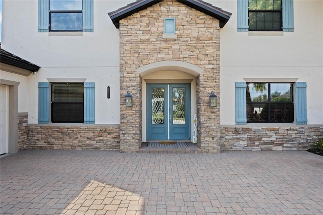 property entrance with stone siding, french doors, and stucco siding