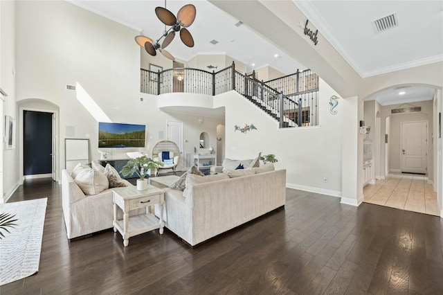 living area with baseboards, crown molding, arched walkways, and hardwood / wood-style floors