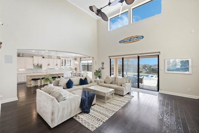 living area with baseboards, a ceiling fan, and dark wood-style flooring