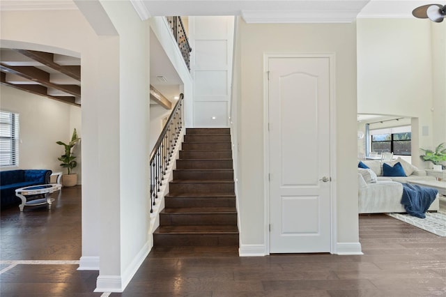 staircase with ornamental molding, wood finished floors, and baseboards