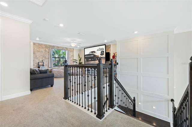 corridor with carpet, visible vents, a decorative wall, ornamental molding, and an upstairs landing