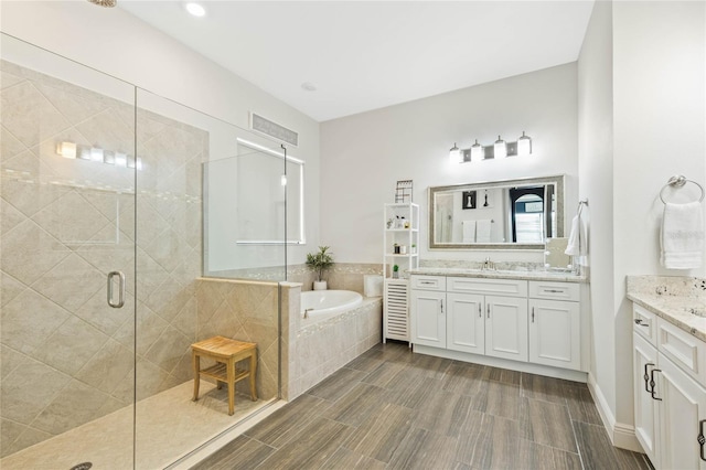 full bathroom with a garden tub, a stall shower, two vanities, and a sink