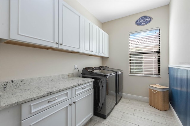 clothes washing area featuring washing machine and clothes dryer, cabinet space, and baseboards