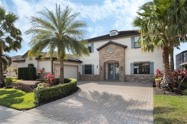 view of front of property featuring decorative driveway, stone siding, an attached garage, and stucco siding