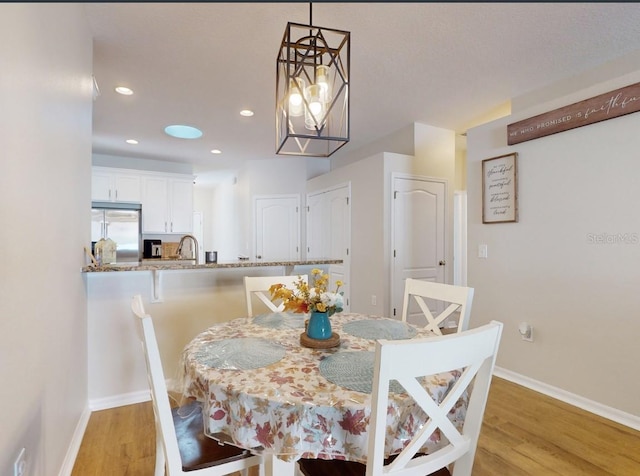 dining room featuring sink, light hardwood / wood-style flooring, and a chandelier