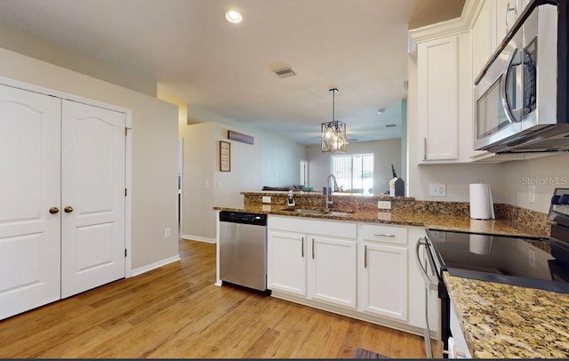 kitchen with sink, stainless steel appliances, dark stone counters, and white cabinets