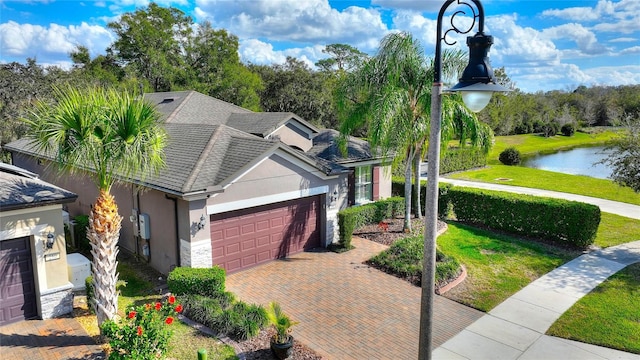 single story home featuring a garage, a front lawn, and a water view