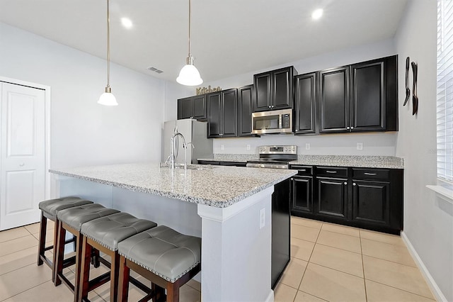 kitchen with appliances with stainless steel finishes, a breakfast bar, pendant lighting, sink, and a kitchen island with sink