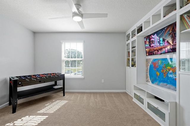 rec room with ceiling fan, built in features, light colored carpet, and a textured ceiling