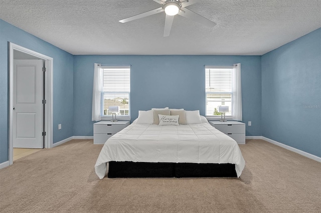 bedroom with ceiling fan, multiple windows, light carpet, and a textured ceiling