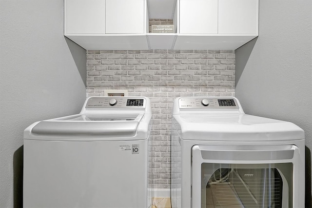 clothes washing area with washing machine and dryer and cabinets