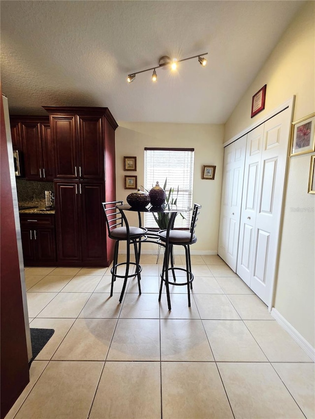 tiled dining area featuring vaulted ceiling and a textured ceiling