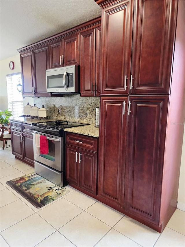 kitchen featuring light stone counters, appliances with stainless steel finishes, decorative backsplash, and light tile patterned floors