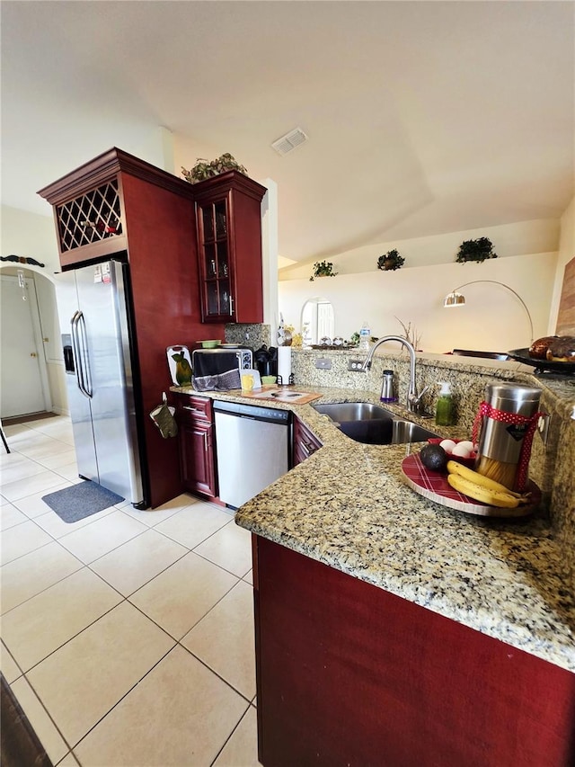 kitchen with sink, light stone counters, light tile patterned floors, kitchen peninsula, and stainless steel appliances