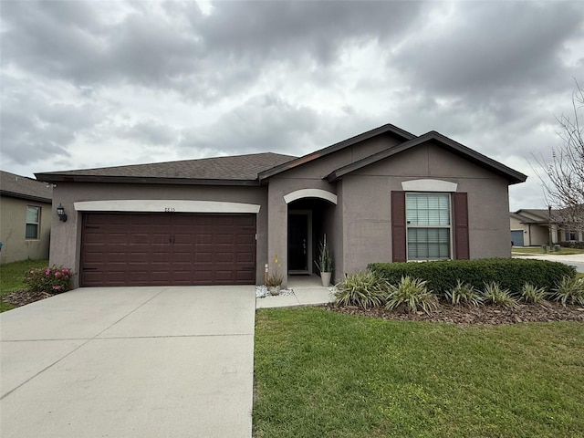 ranch-style house with a front lawn, concrete driveway, an attached garage, and stucco siding