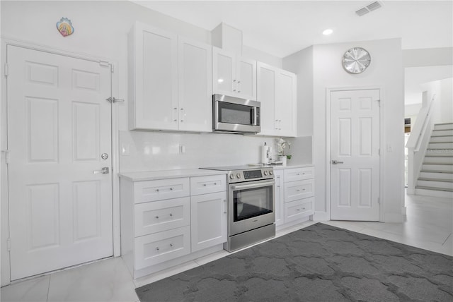 kitchen featuring decorative backsplash, white cabinets, and appliances with stainless steel finishes