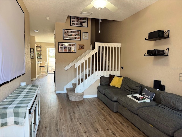 living room featuring hardwood / wood-style flooring, ceiling fan, and a textured ceiling