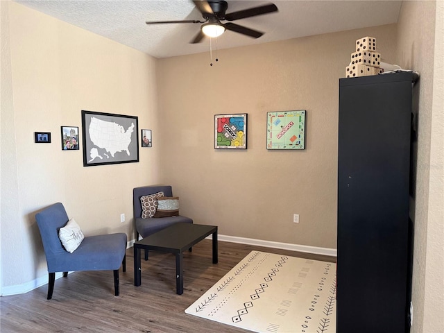 living area with ceiling fan, wood-type flooring, and a textured ceiling