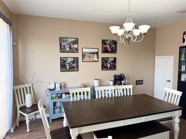 dining room with dark wood-type flooring and a chandelier