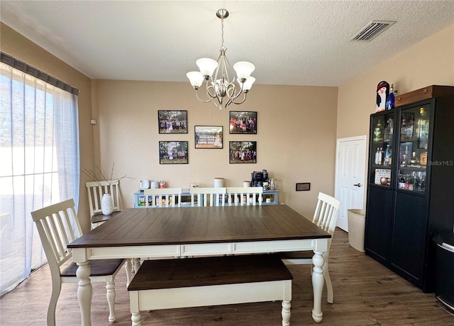 dining room with dark wood-type flooring, a chandelier, and a textured ceiling