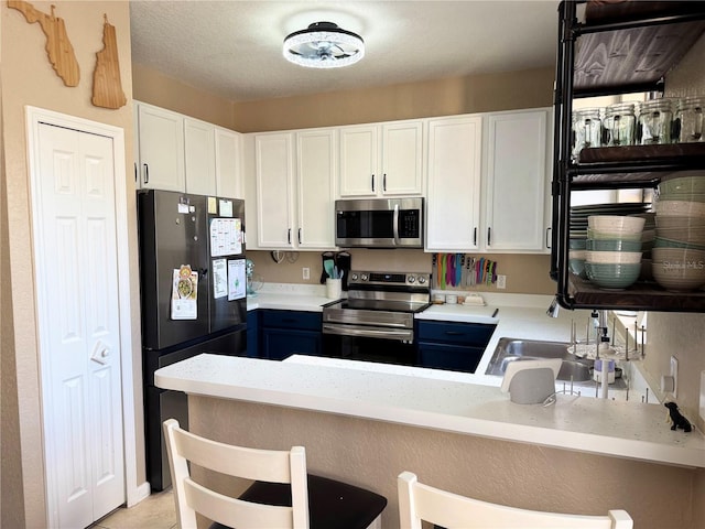 kitchen with white cabinetry, stainless steel appliances, and kitchen peninsula