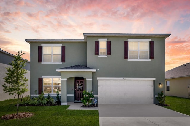 traditional-style home featuring an attached garage, a lawn, driveway, and stucco siding