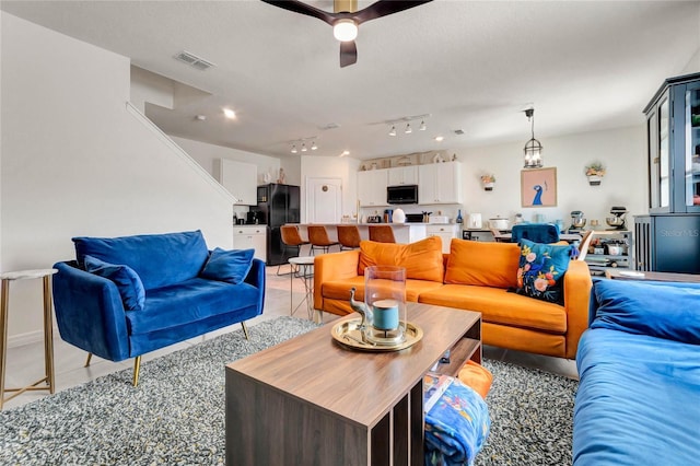 living area with light tile patterned floors, visible vents, track lighting, and a ceiling fan