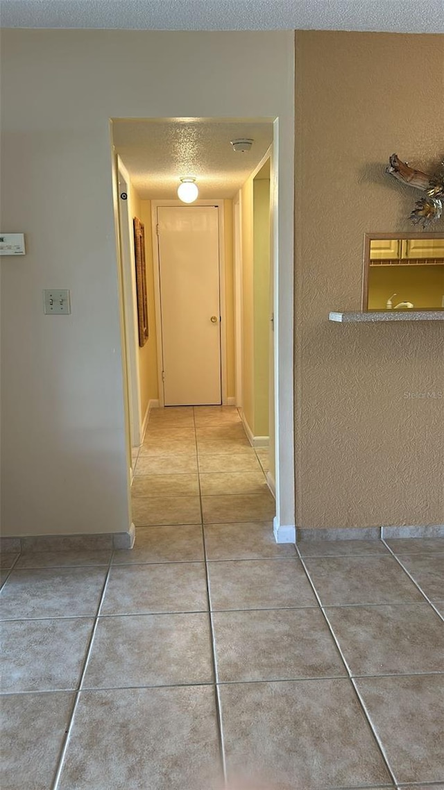 corridor featuring tile patterned flooring and a textured ceiling