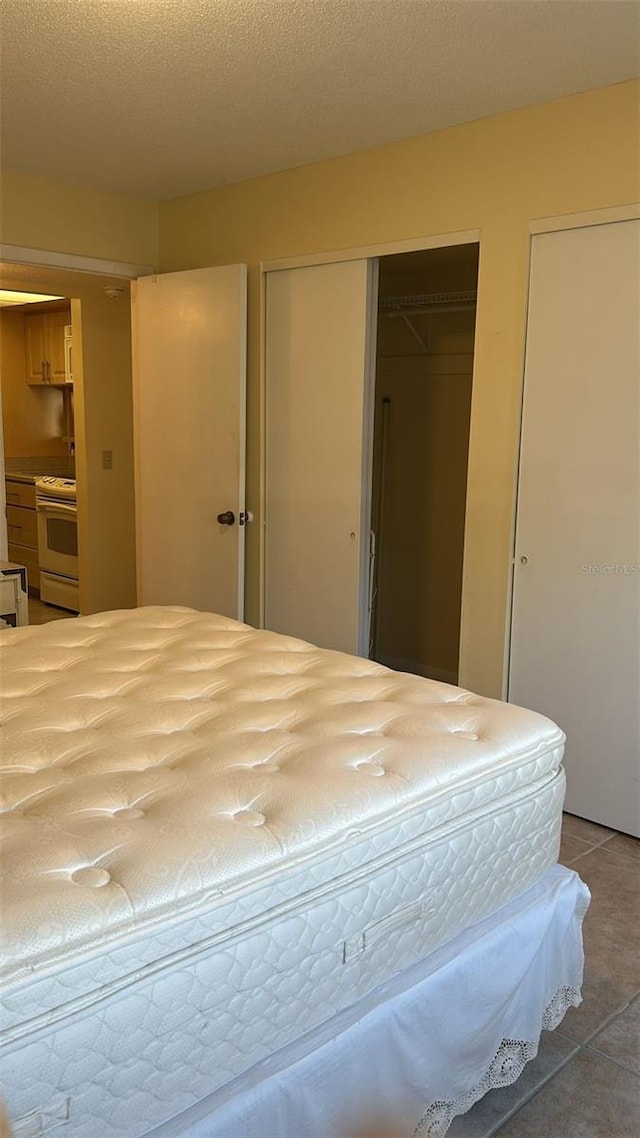 tiled bedroom with multiple closets and a textured ceiling