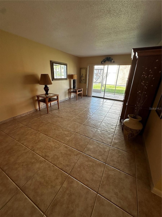 unfurnished room featuring a textured ceiling and dark tile patterned flooring